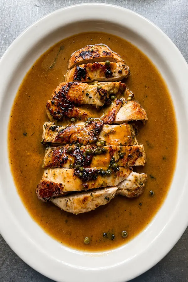 Pechuga de pollo rebanada en salsa sobre platón ovalado