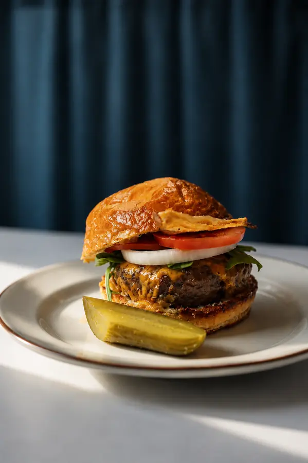 Hamburguesa con pepinillo sobre fondo de cortina azul