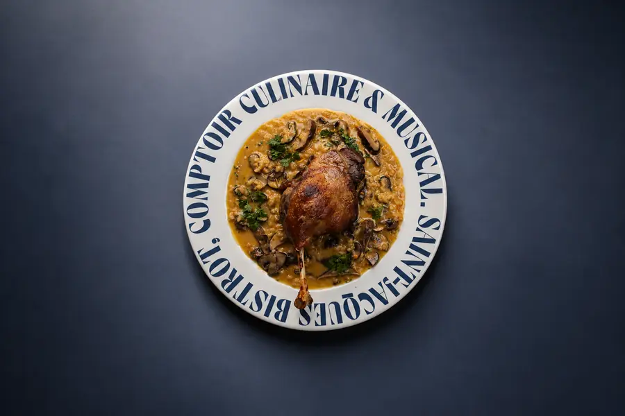 Confit servido en plato Comptoir sobre fondo azul