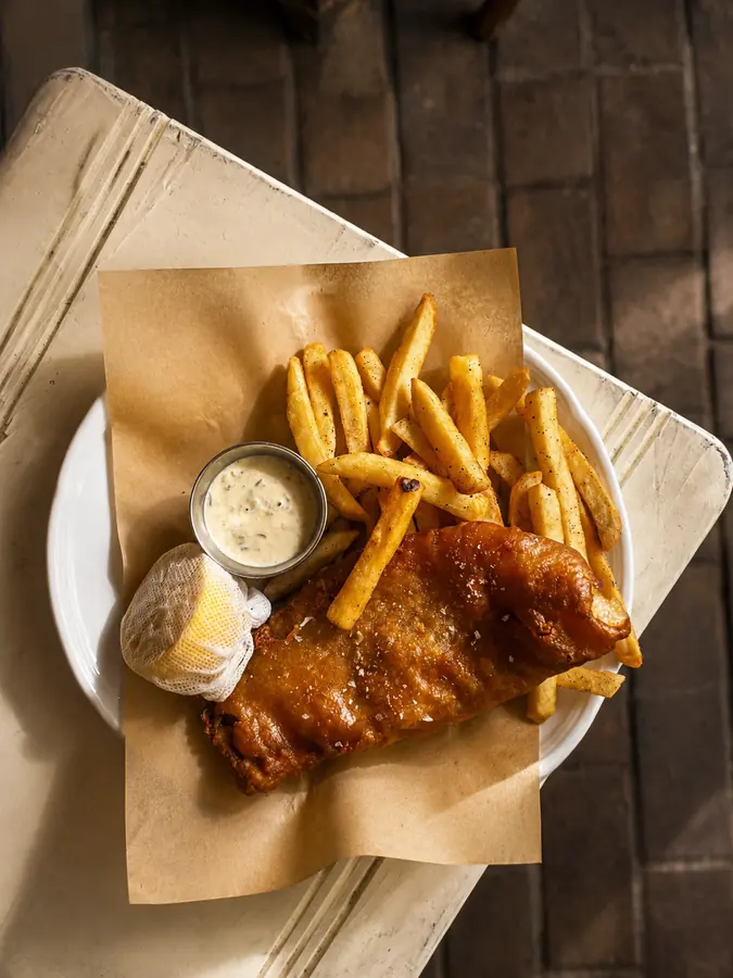Fish and chips servido en papel con salsa tártara