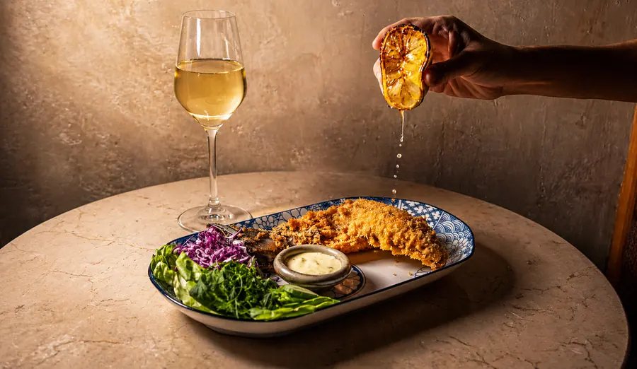 Plato servido junto a copa de vino, salsa al momento