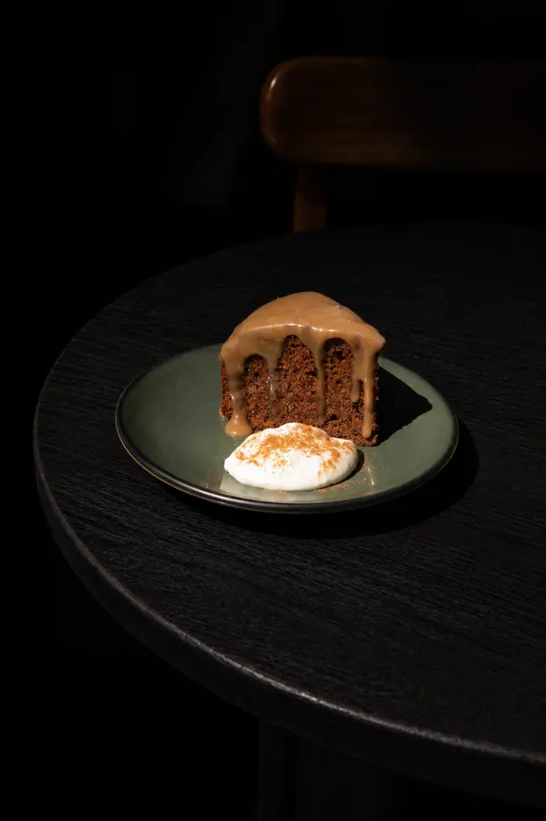 Tarta servida en plato verde sobre mesa oscura